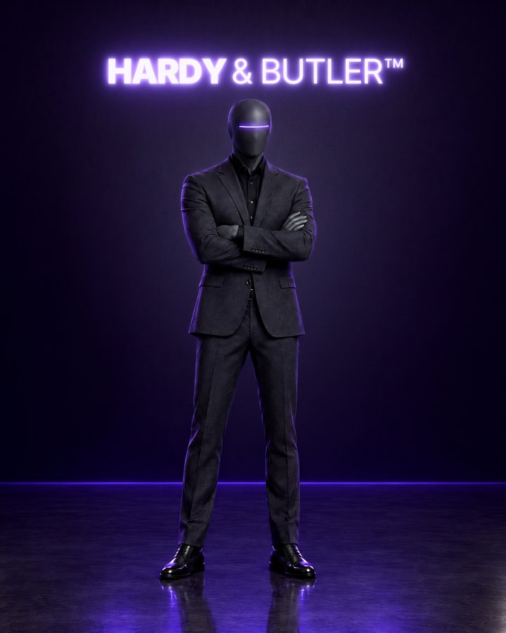 Hardy, pictured as an AI agent: a faceless graphite figure in a charcoal suit and black shirt, arms folded, under the lit Hardy & Butler sign.