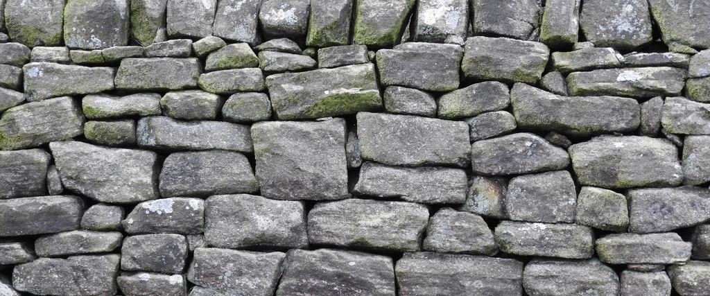 A dry stone wall, every stone chosen and placed by hand, no mortar holding it.